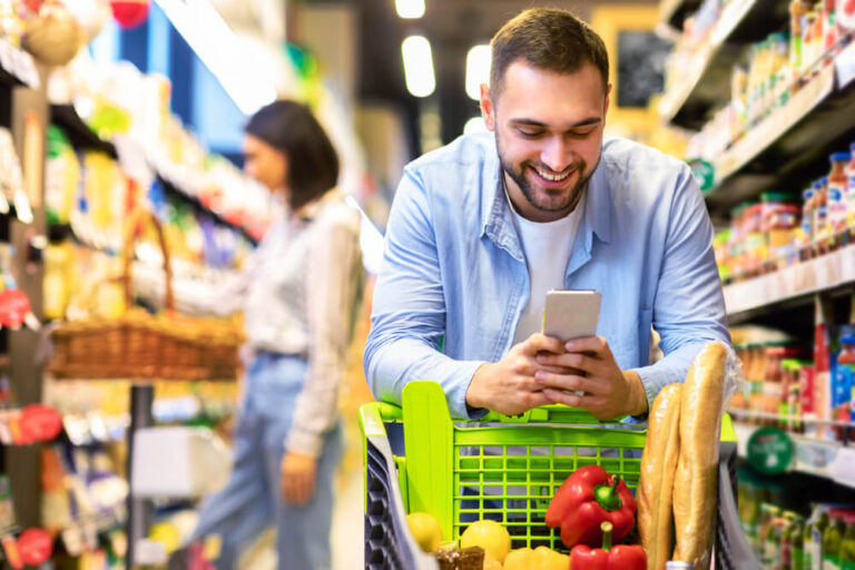 homem olhando o celular durante compras de mercado