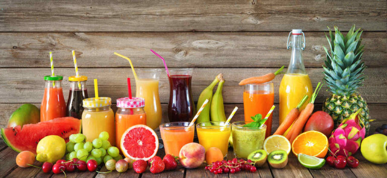 muitos sucos e frutas em cima de uma mesa